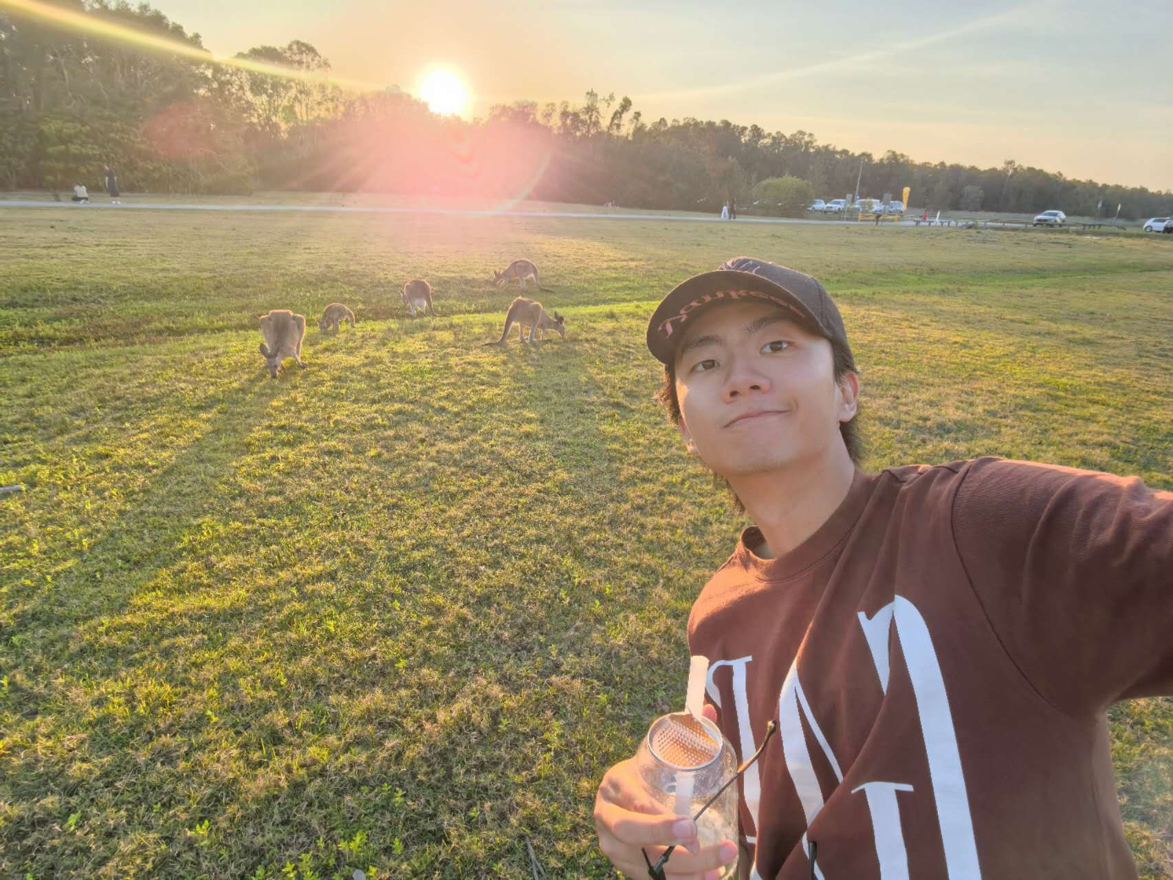 Selfie with wild kangaroos on a lawn at sunset