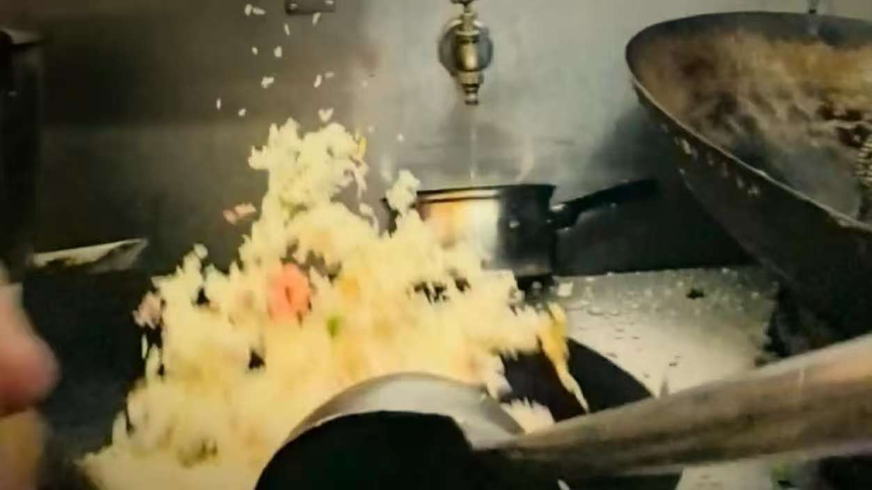 Cooking fried rice with a large wok in a commercial kitchen